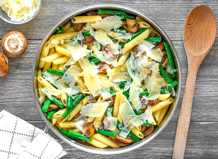 penne green bean meal from above on a table with a wooden spoon 