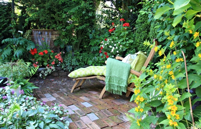 relaxation spot in a garden landscaping with a wooden chair with a blanket and pillow