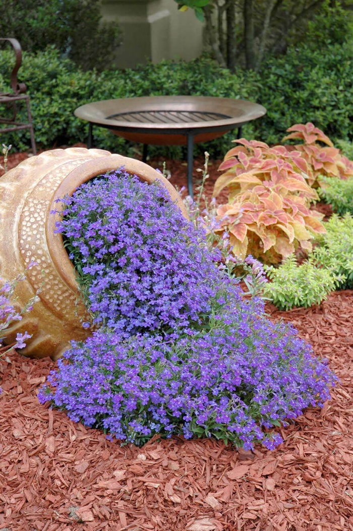 spilling flowers from a huge ceramic jug purple flowers in a garden