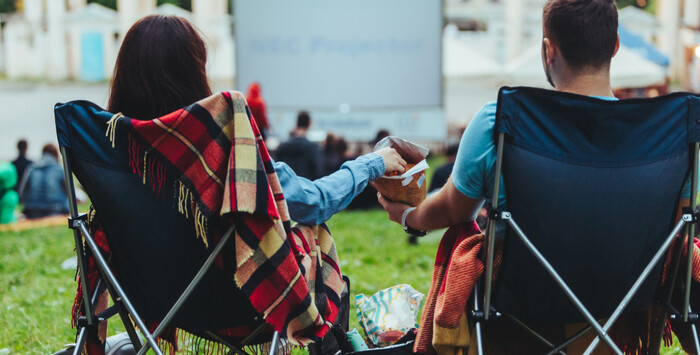 summer movies otudoor cinema couple sitting eating popcorn and watching