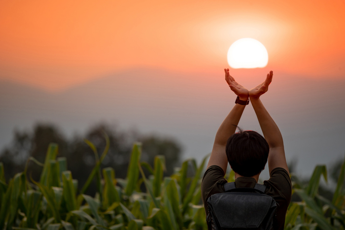 summer solstice day man holding the sun with two hands out in a field