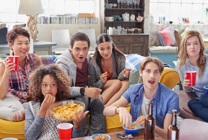 friends watching a movie in a living room with snacks