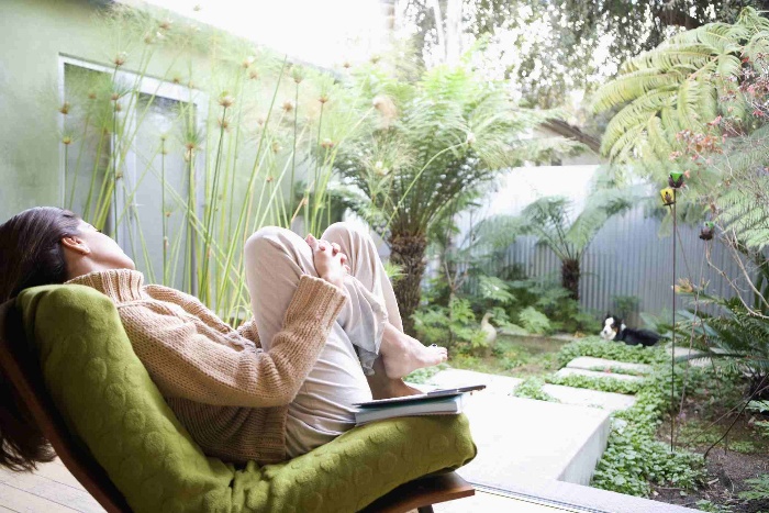 woman patio sitting in a green chair looking at the garden