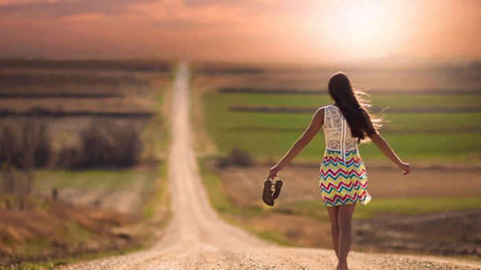 Gratitude pandemic summer woman in a dress walking barefoot down a path between green fields