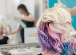 Hairdresser spraying hair spray on the female finished haircut. She love her new look and watching herself in the mirror. Love unicorn and rainbow hair.