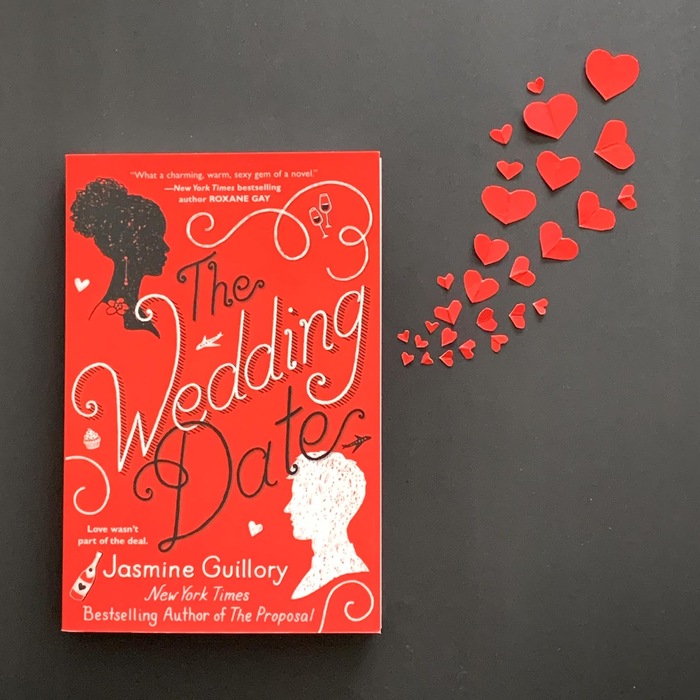 The wedding date red book on a dark surface with hearts going out of it