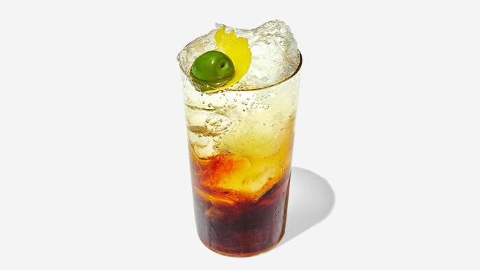 amaro and soda cocktail in a glass filled with ice and decorated with fruits