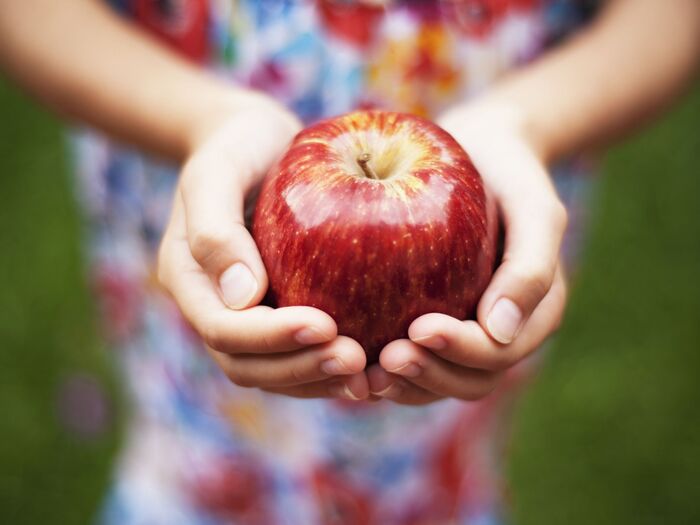 child with a colorful dress holding a red apple in their hands