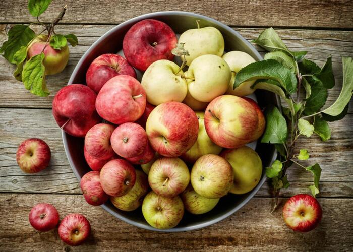 a large container full with different apples red and white on a wooden table