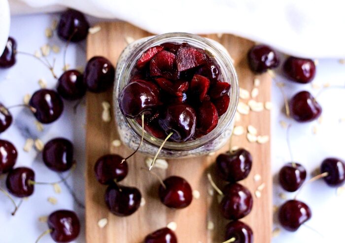 cherries in a jar and on a wooden board on a table