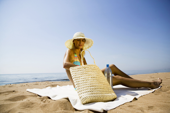 Young woman on beach, wearing sunhat