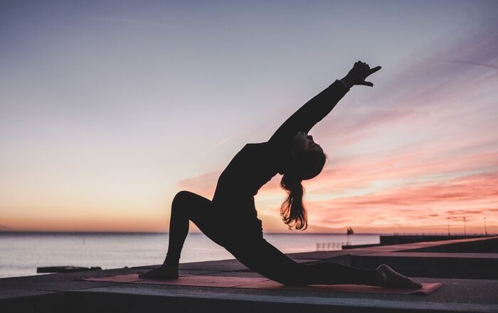 daily yoga woman doing yoga at subset close to the sea