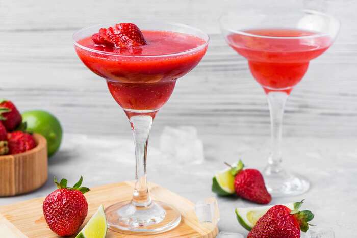 red daiquiri in tall glasses decorated with strawberries and other fruit