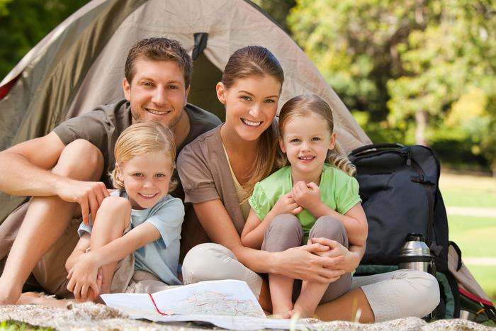 family camping family of four in front of a tent in a park