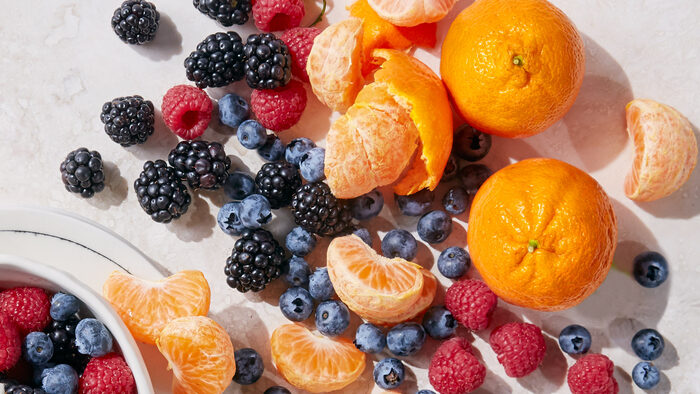 fruits on a table blueberries blackberries and tangerines spread on a table