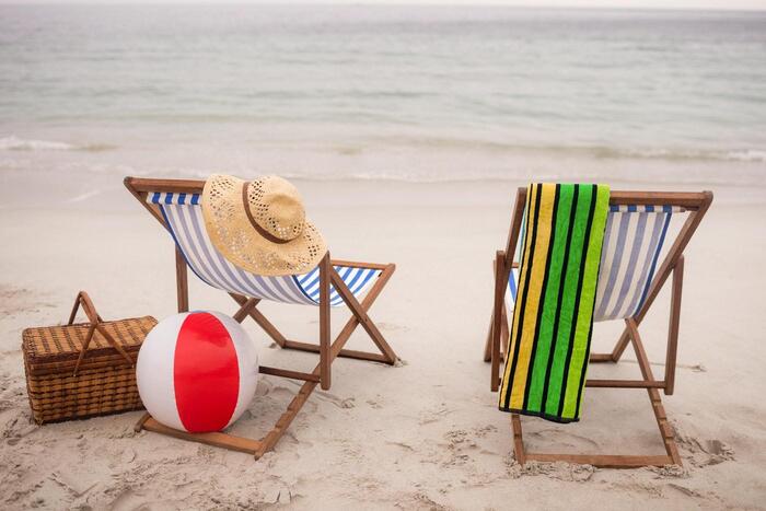 going to the beach two chairs with a towel sun hat beach ball and a basket