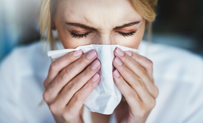 hay fever sneezing woman with a white tissue in front of her nose sneezing in it