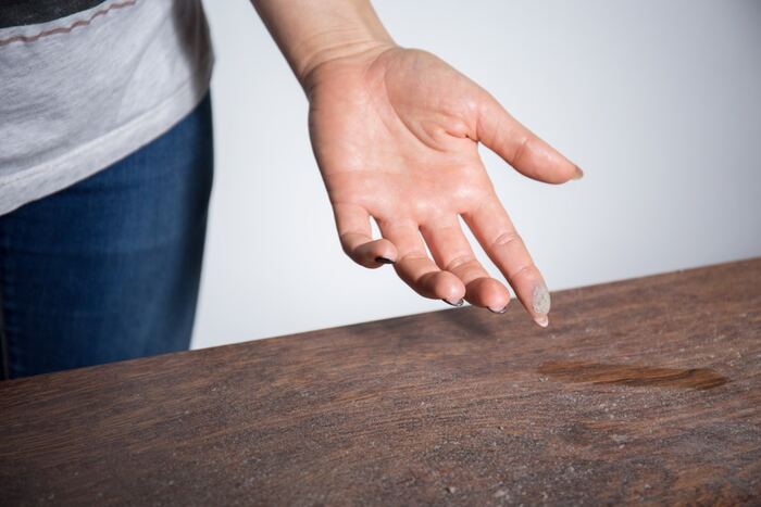 home dust woman in jeans checking the dust on a wooden surface with her fingers