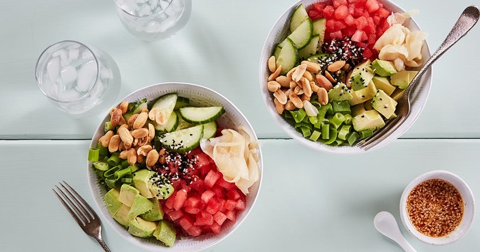 light summer meal two bowls with vegetables on a white table with glasses with ice water