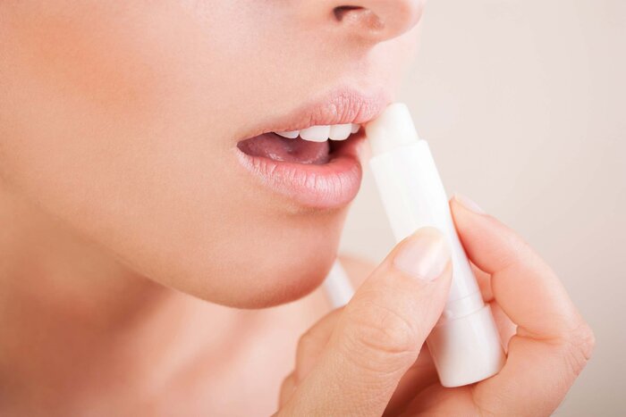 woman applying lip balm on her lips close up