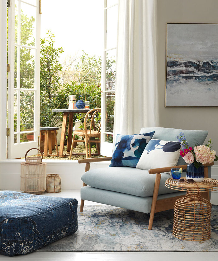 artistic living room with light blue accents decorative pillows painting on the wall and a terrace