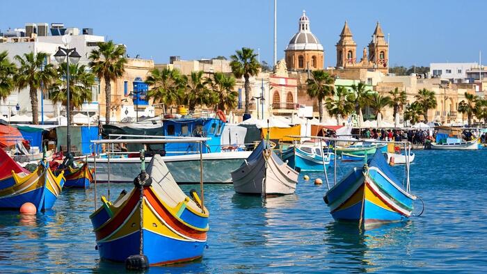 malta views colorful boats palm trees and domes in the background
