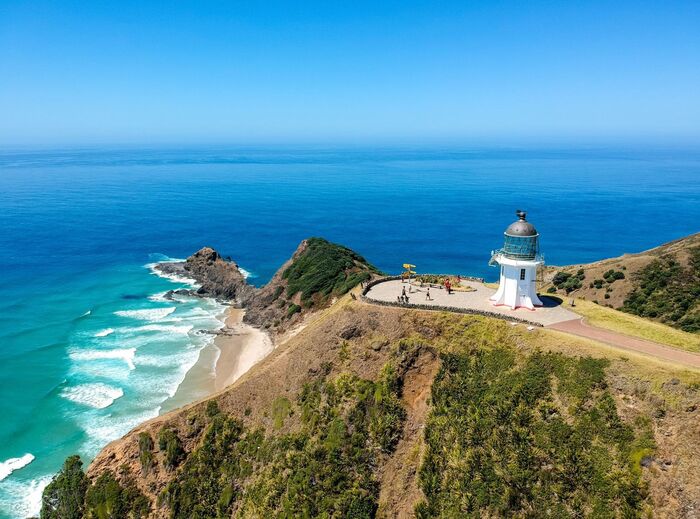 new zealand cape with a lighthouse overlooking the blue sea white waves crashing in the rocky shore