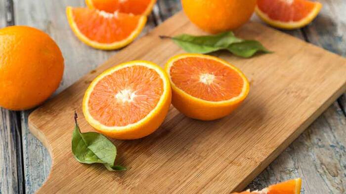 oranges citrus fruits wooden table with a wooden cutting board and slices of oranges also orange leaves