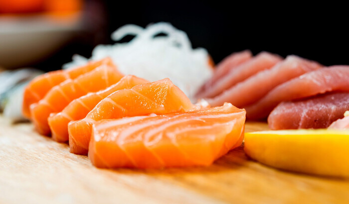 salmon and tuna fish slices ion a wooden table with lemon 