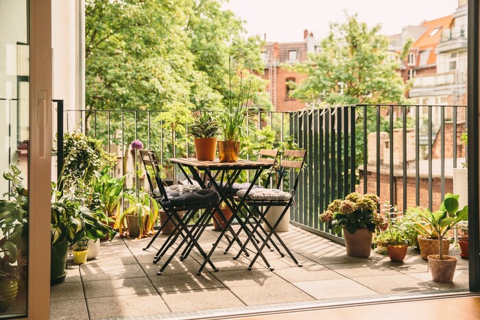 small balcony oasis in the city with living plants tiles on the floor and a small table with chairs 