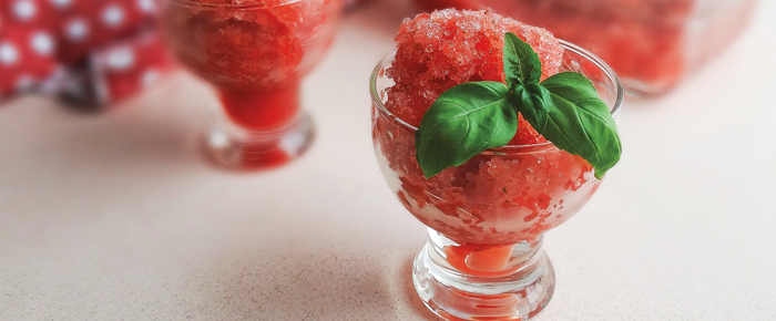 watermelon red sorbet in a glass cup with basil leaf as decoration