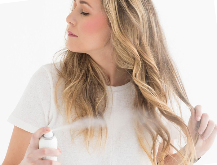 spray summer blond woman in white clothes spraying a refreshing spray in her hair