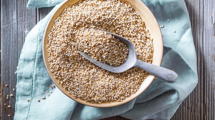 steel cut oats in a large bowl on a light blue towel on a wooden table with a large spoon