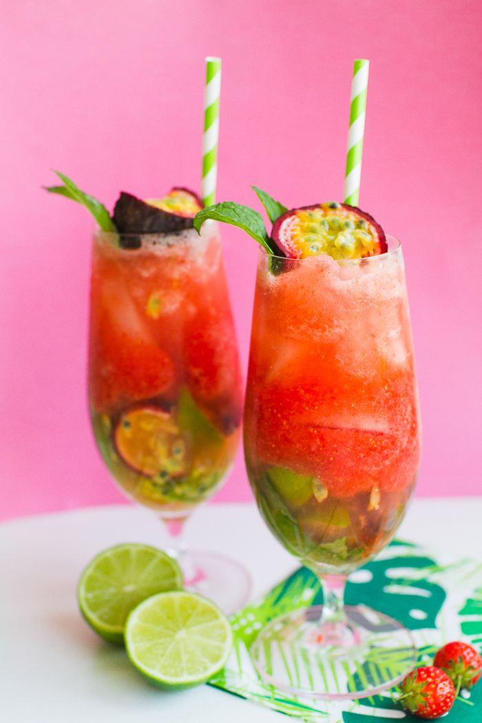 strawberry mojito tall glasses with straws filled with red mojito decorated with tropical fruits 