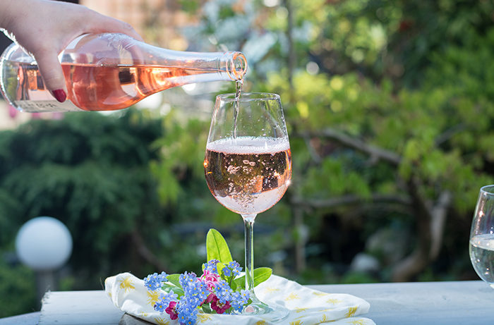woman pouring rose wine to a glass in the garden