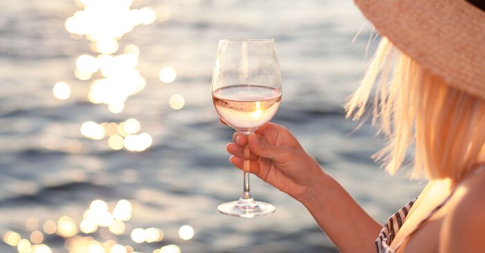 white summer wines woman holding a glass of white wine with the sea in the background
