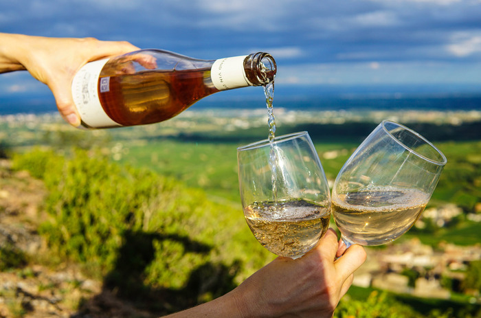 white wine person pouring white wine out of a bottle into two wine glasses