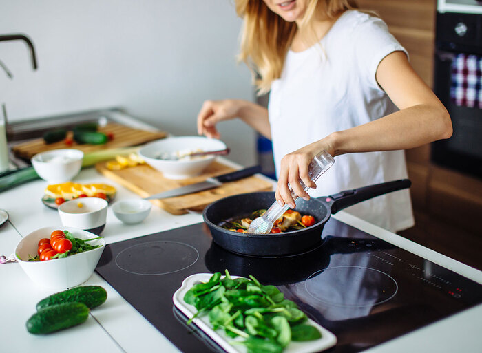 woman in white top cooking in a kitchen vegetable dish