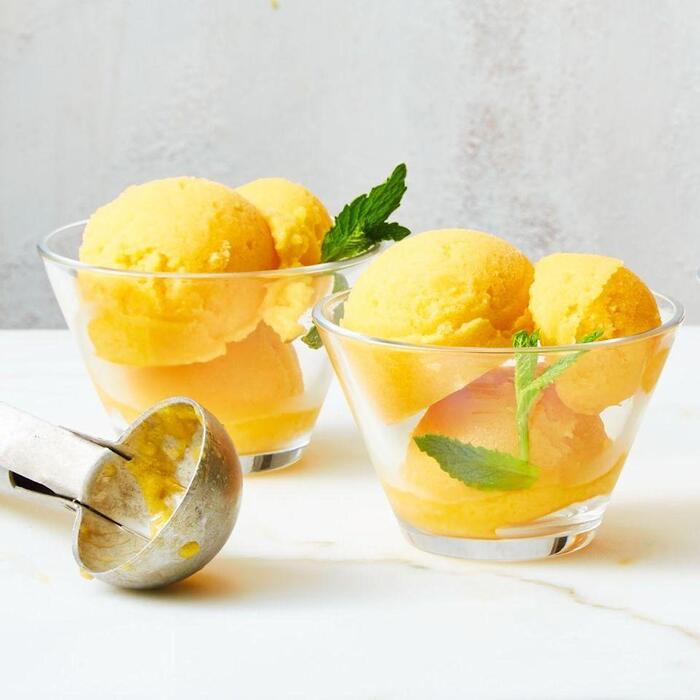 bright yellow ice cream with mint decoration on glass cups on a light background