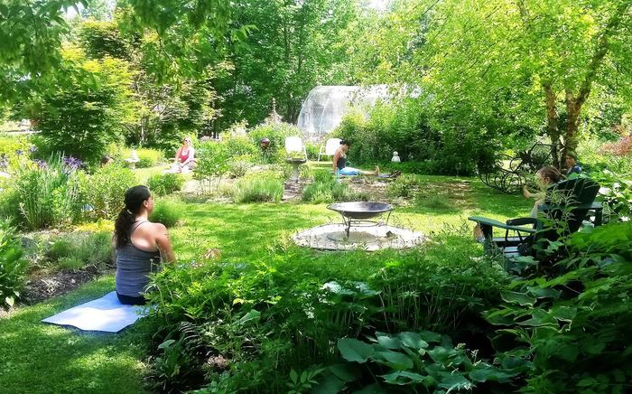 garden with women doing yoga outdoors on yoga mats surrounded by greenery