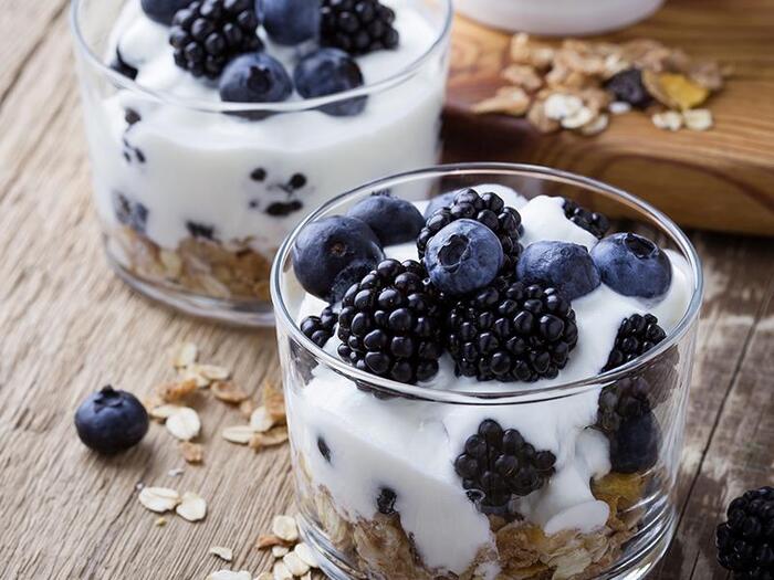 yoghurt with oats and blueberries and blackberries on a wooden table close up