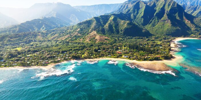 Kona Hawaii beach with crushing white waves and green coastline with high cliffs