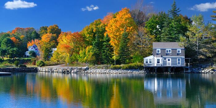 a lake property on a large lake with a forest in the background with fall leaves and trees