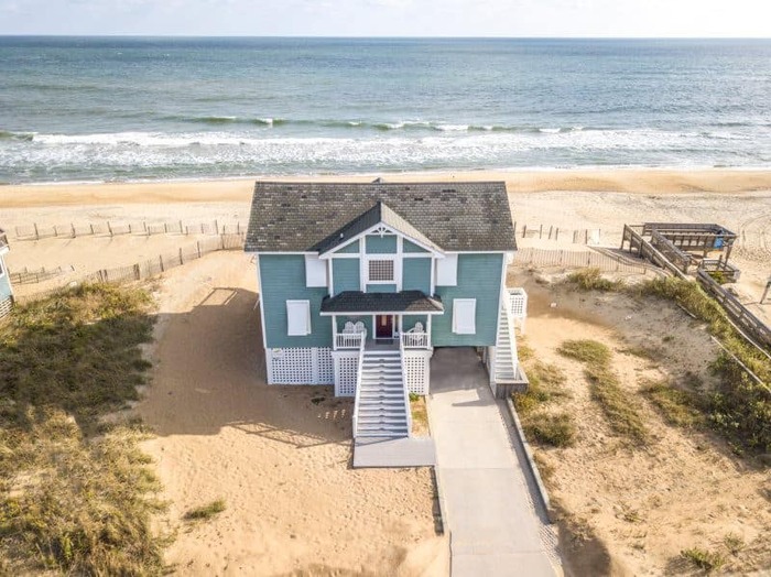 blue beach house at the first line of the beach sea in the background with crushing waves