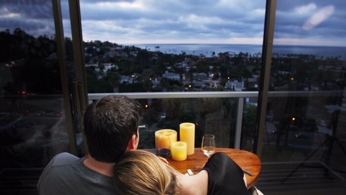 couple on a terrace cuddling and overlooking a sea town with the sea in the background candles on a table in front