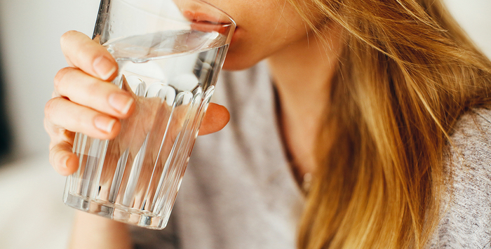 blonde woman with long hair drinking water from a large glass