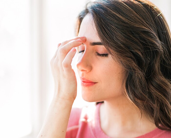 eft tapping woman with dark brown hair and a pink shirt doing tapping on her forehead 