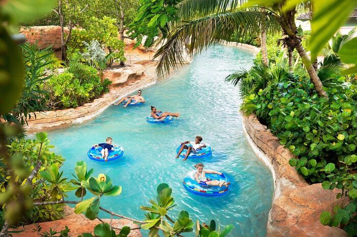 family activities in a long pool surrounded by tropical plants family members enjoying the ride