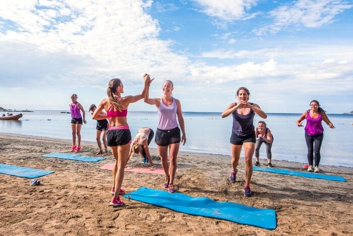 fitness vacation women on the beach with their mats working out