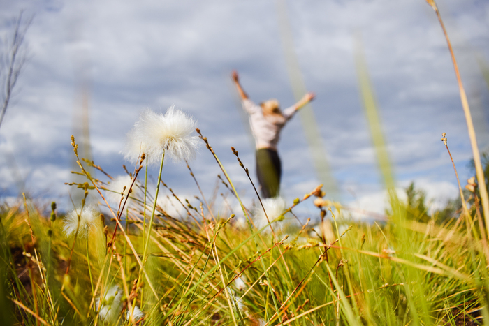 girl in nature jumping and having fun in the background close up of grass and flowers